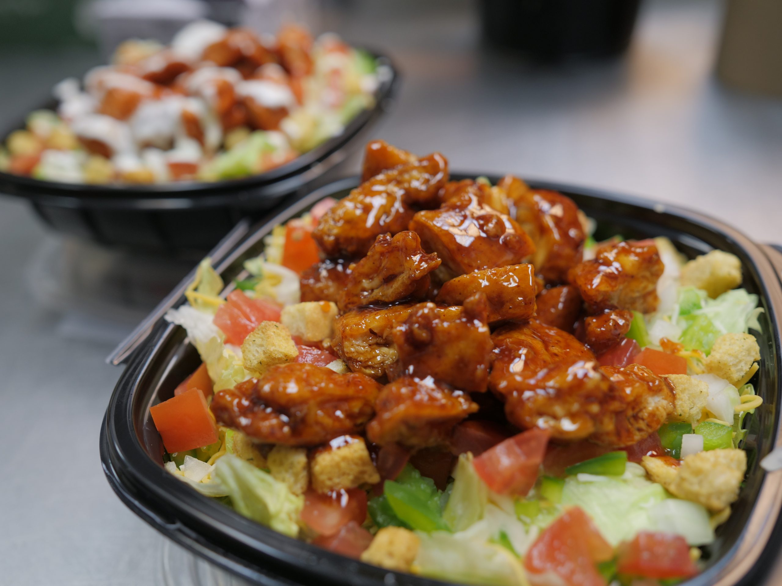 Two bowls of bbq chicken salad on a counter.