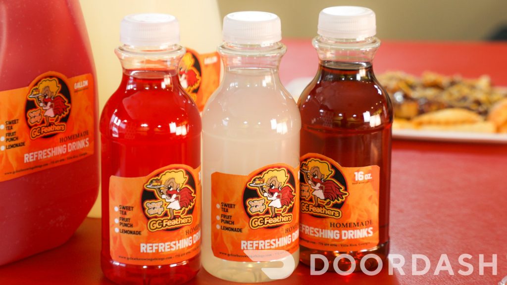 Assorted bottles of homemade drinks with a branded label on a table, with a doordash logo visible.
