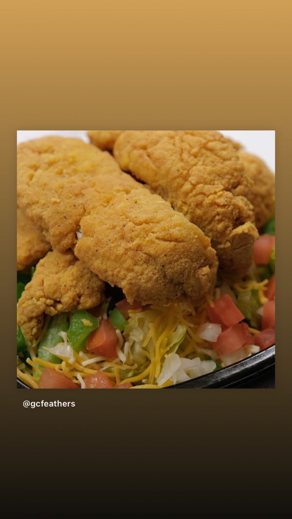 Fried chicken tenders served over a bed of salad with shredded cheese and diced tomatoes.