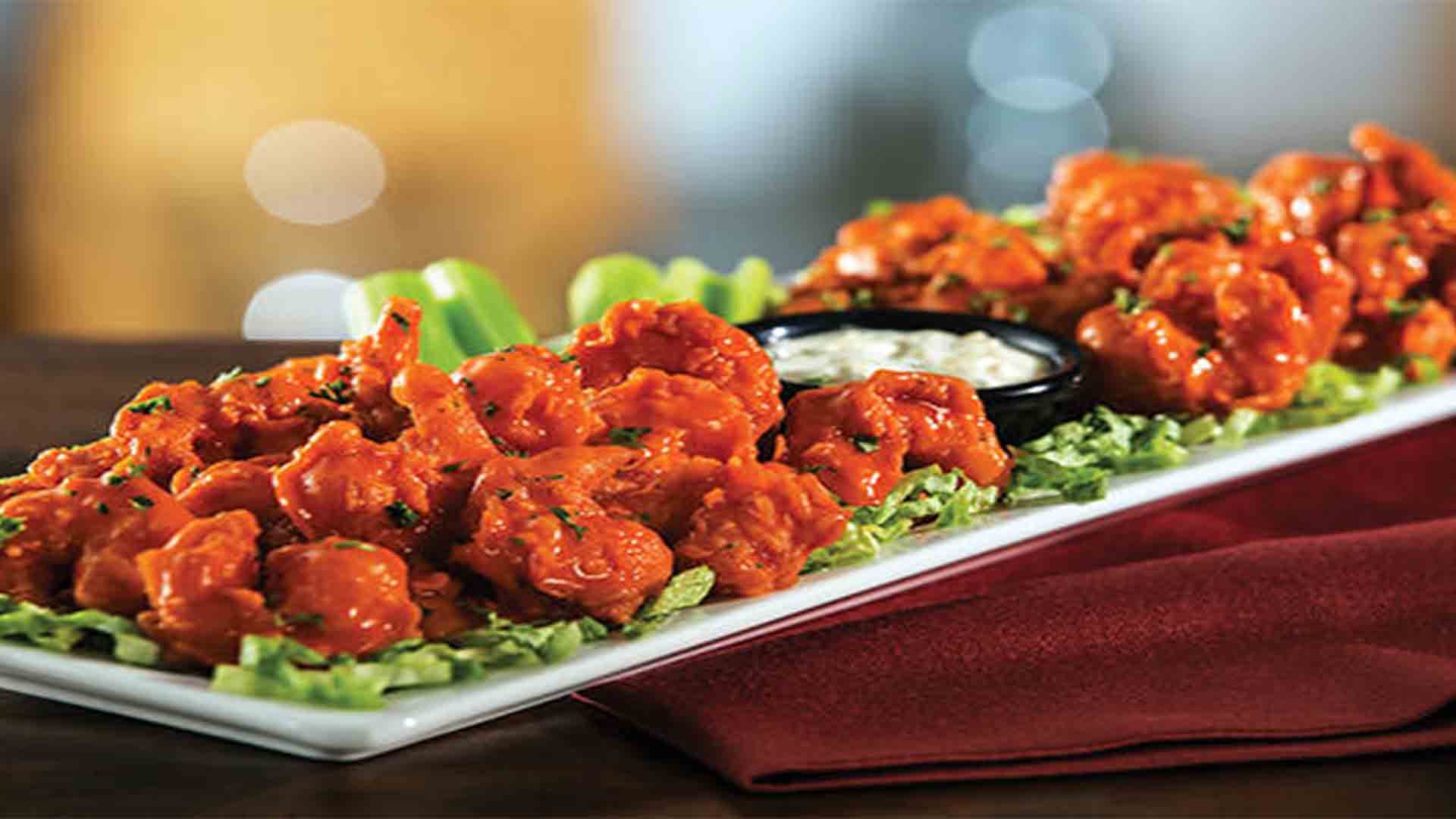 A platter of buffalo wings served with celery and dipping sauce.