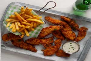 A serving of chicken tenders with a side of fries and dipping sauce on a metal tray.
