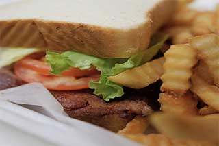A close-up of a bacon lettuce and tomato sandwich with crinkle-cut fries.