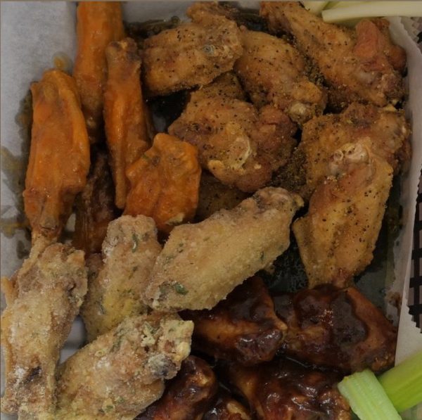 Assorted 70 wings with celery sticks in a takeout box.