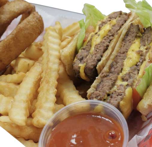 A cheeseburger with lettuce and tomatoes, accompanied by french fries, onion rings, and a small cup of ketchup.