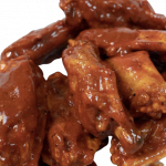 A pile of buffalo wings coated in a glossy, reddish-brown sauce.