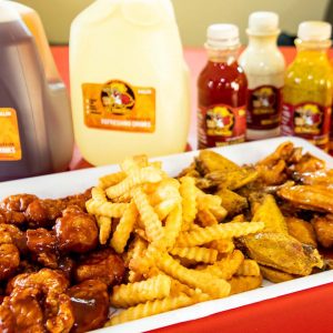 Assortment of fried chicken and waffle fries served with a selection of sauces and beverages.