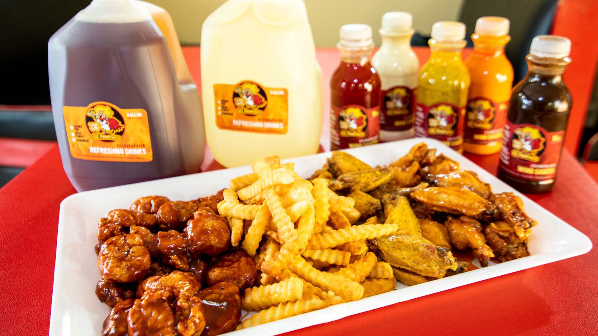 Assortment of fried chicken and waffle fries served with a selection of sauces and beverages.