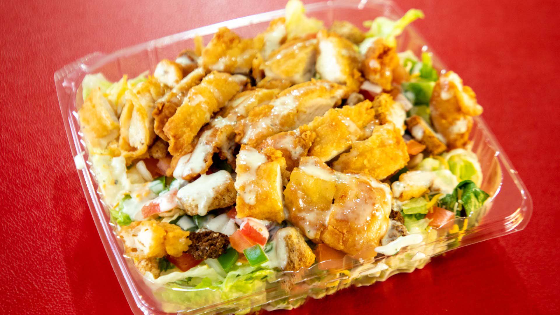 A crispy chicken salad with ranch dressing in a plastic container.