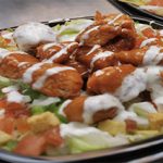 A buffalo chicken salad with croutons and drizzled dressing.
