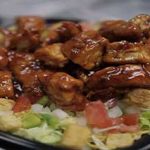 Glazed chicken wings atop a bed of salad with croutons and diced tomatoes.