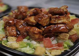 Glazed chicken wings atop a bed of salad with croutons and diced tomatoes.