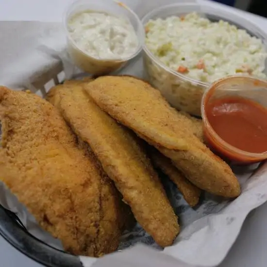 Four pieces of fried fish served with coleslaw and a side of sauce.