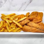 A plate of breaded fish fillets with a side of crinkle-cut fries.
