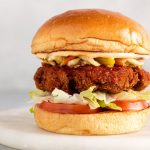 A chicken sandwich with lettuce, tomato, and sauce on a bun.